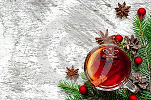 Christmas hot mulled wine with cinnamon, anise and fir tree branches on white wooden background.