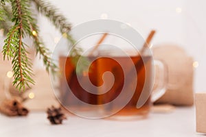 Christmas hot tea in glass cup on white wooden table with christmas decoration. Winter background