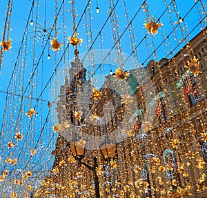 Christmas illumination decoration in Moscow on Nikolskaya street. Yellow stars, garlands. Holiday New Year in the city