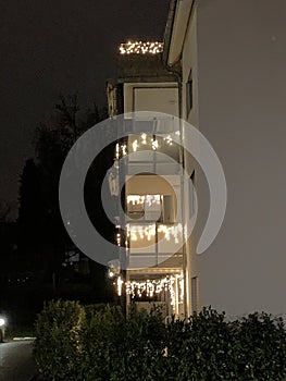 Christmas illumination or light decoration on balconies on a residential building in lateral view.