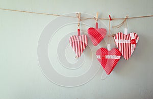 Christmas image of fabric red hearts hanging on rope in front of wooden background. retro filtered