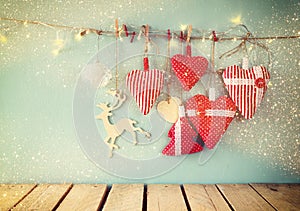 Christmas image of fabric red hearts and tree. wooden reindeer and garland lights, hanging on rope