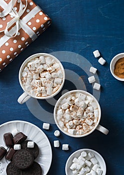 Christmas inspiration table - hot chocolate with marshmallows, cookies, gift box, christmas ornament reindeer on a blue background