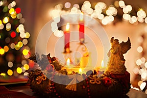 Christmas Interior with Candles, Wreath and Angel on Table. Winter Holiday Room Background with Lights and Fireplace. Mystery Xmas