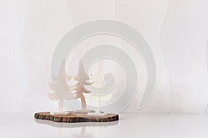 Christmas interior decor. Three toy Christmas trees made of plywood on tree cut, white wall.