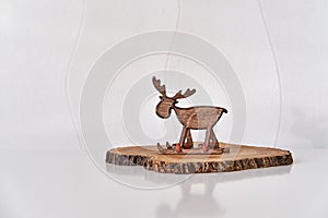 Christmas interior decor. Toy deer on skiing on tree cut, white wall.