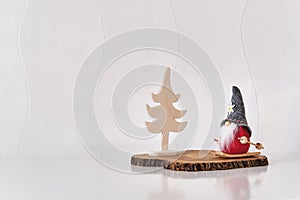 Christmas interior decor. Toys, Christmas gnome on skiing, Christmas tree, on tree cut, white wall.