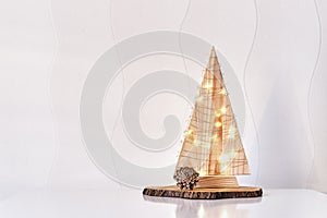Christmas interior decor.Wooden stylized Christmas tree with lighted garland,pine cone,on tree cut