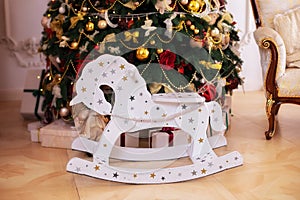 Christmas interior of living room with horse rocking chair and Christmas tree. Scandinavian wooden toy. Wooden horse rocking chair