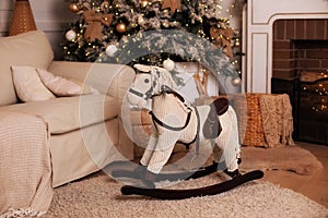 Christmas interior of room with horse rocking chair and decorated Christmas tree. horse rocking chair in Xmas room for child. Cozy