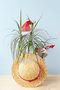 Christmas in july vertical composition. small palm, summer staw hat, santa hat