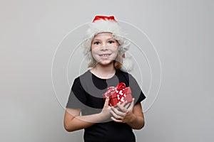 Christmas kid girl in Santa hat holding red gift box on white background, Xmas portrait