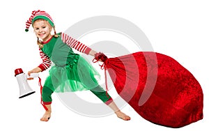 Christmas Kid pulling Santa Bag Full of Gifts. Funny Girl in Elf Costume with Red Huge Sack packed Xmas Presents. Christmas Child