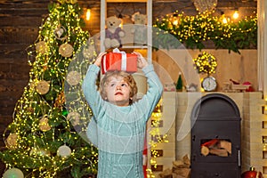 Christmas kids - happiness concept. Little Santa Claus gifting gift. Home Christmas atmosphere. Cheerful cute child
