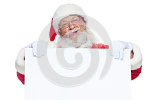 Christmas. Kind Santa Claus in white gloves with his tongue sticking out holds an empty white cardboard and shows faces