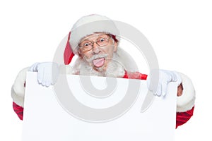 Christmas. Kind Santa Claus in white gloves with his tongue sticking out holds an empty white cardboard and shows faces