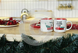 Christmas kitchen decor. 2 cups with a festive pattern and an inscription are on the table