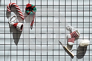 Christmas Knit Toys. Handmade DIY Crochet hat, lollipop, donut and sock and female hand on checkered white background