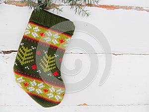 Christmas knitted mini sock with winter ornament on vintage white wooden background.