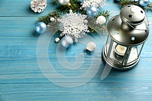Christmas lantern with burning candle and festive decor on light blue wooden table. Space for text