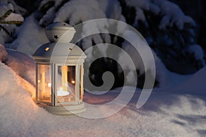 christmas lantern with a burning candle in the night forest