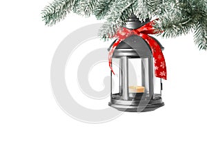 Christmas lantern with candle hanging on snowy fir tree branch against light background. Space for text