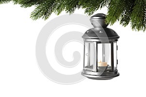 Christmas lantern with candle hanging on snowy fir tree branch against white background