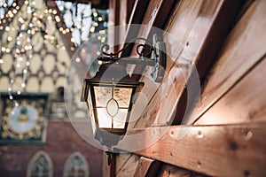 Christmas lantern. Festive illumination on a wooden house.