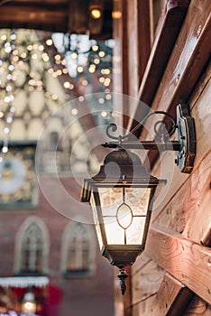 Christmas lantern. Festive illumination on a wooden house.