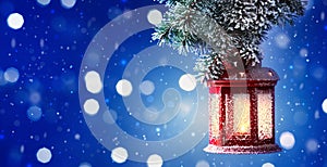 Christmas lantern hanging on snow covered fir branches. Winter cozy scene. Banner format