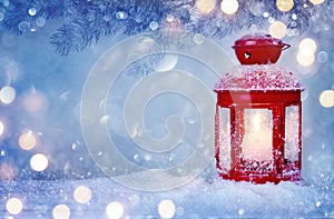 Christmas lantern on snow with frosen fir branch in light