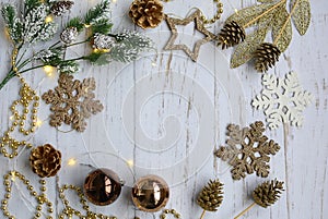 Christmas layout of brown christmas toys, snowflakes, spruce branch, gilded cones and garland on a light wooden background