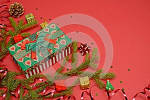 Christmas layout on a red background with space for text and design. Gift box, fir branches, garlands and decorative presents
