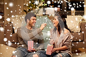 Happy couple eating popcorn at home