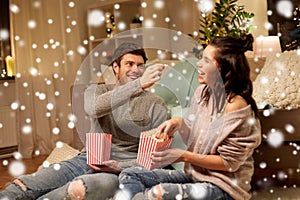 Happy couple eating popcorn at home