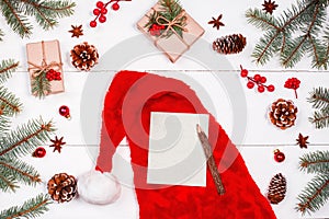 Christmas letter on holiday background with red Santa hat, Fir branches, pine cones, red decorations