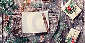 Christmas letter on wooden background with Christmas gifts, bark texture, pencil, Fir branches, pine cones, red decorations.