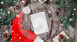 Christmas letter on wooden background with red Santa hat, Fir branches, pine cones, red decorations. Xmas and Happy New Year