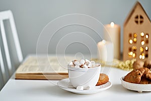 Christmas light gray background with copy space. Reading book on cozy winter evening with candles
