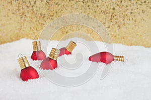 Christmas light ornaments in the snow with gold background