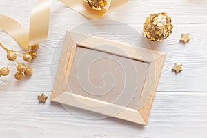 Christmas light wooden frame on a wooden background with ribbon and golden toys. Flat lay, top view photo mockup