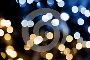 Christmas lights. Bokeh glows on a dark background. Christmas garlands with a blurred focus in the form of gold and blue bokeh