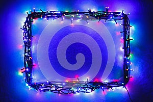 Christmas lights frame on snow background, blue and purple color