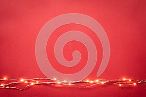 Christmas lights garland border over red background. Flat lay, copy space.