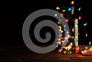 Christmas lights in glass jar on wood, holiday background