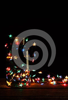 Christmas lights in glass jar on wood, holiday background