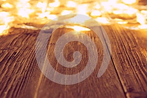 Christmas lights glowing on wooden table or floor background