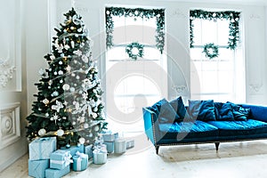 Christmas living room with a Christmas tree, sofa, gifts and a large window. Beautiful New Year decorated classic home interior