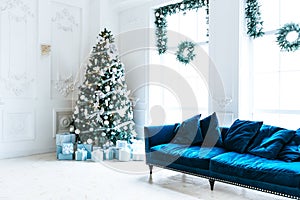 Christmas living room with a Christmas tree, sofa, gifts and a large window. Beautiful New Year decorated classic home interior