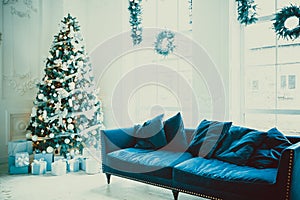 Christmas living room with a Christmas tree, sofa, gifts and a large window. Beautiful New Year decorated classic home interior